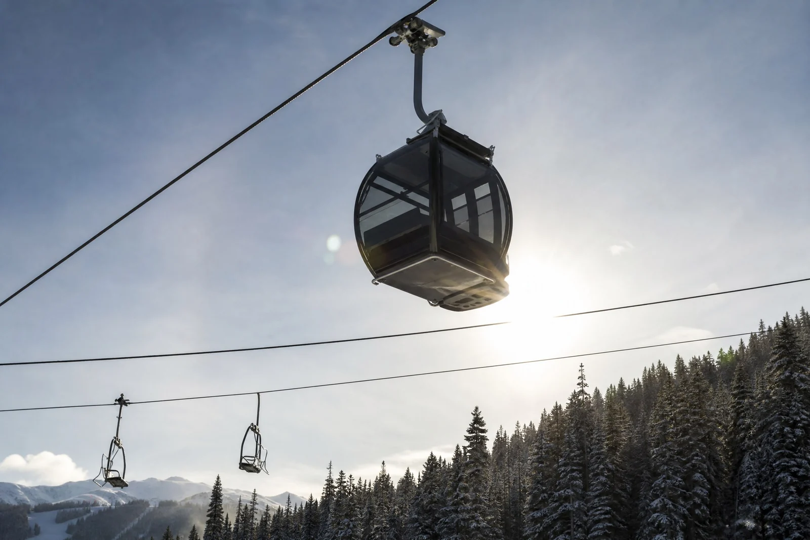 The Alders, Winter gondola cabin against the sun above snow-laden forest, luxury vacation rental in Keystone, Colorado