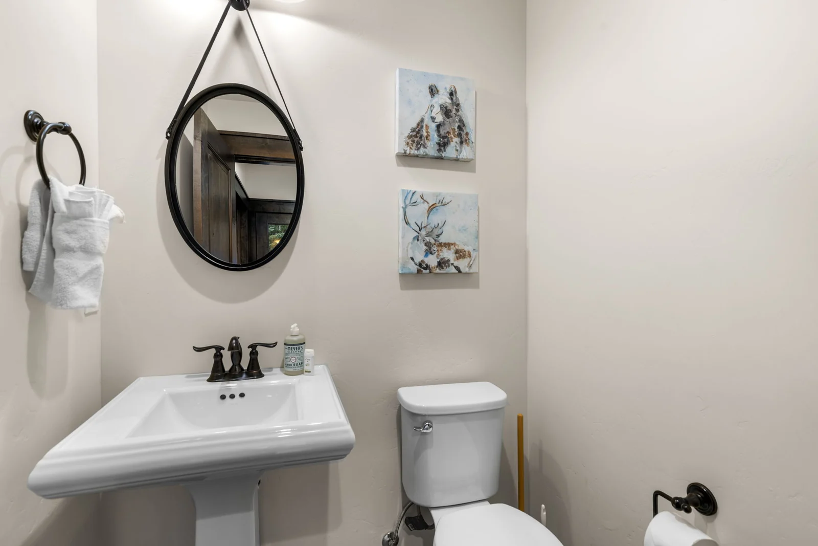 The Alders, Guest powder room with round mirror and pedestal sink, luxury vacation rental in Keystone, Colorado